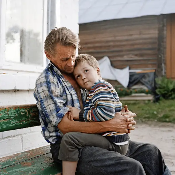Retrato de un hombre con un niño en brazos en el interior del fotolibro “Soon to be gone” 
